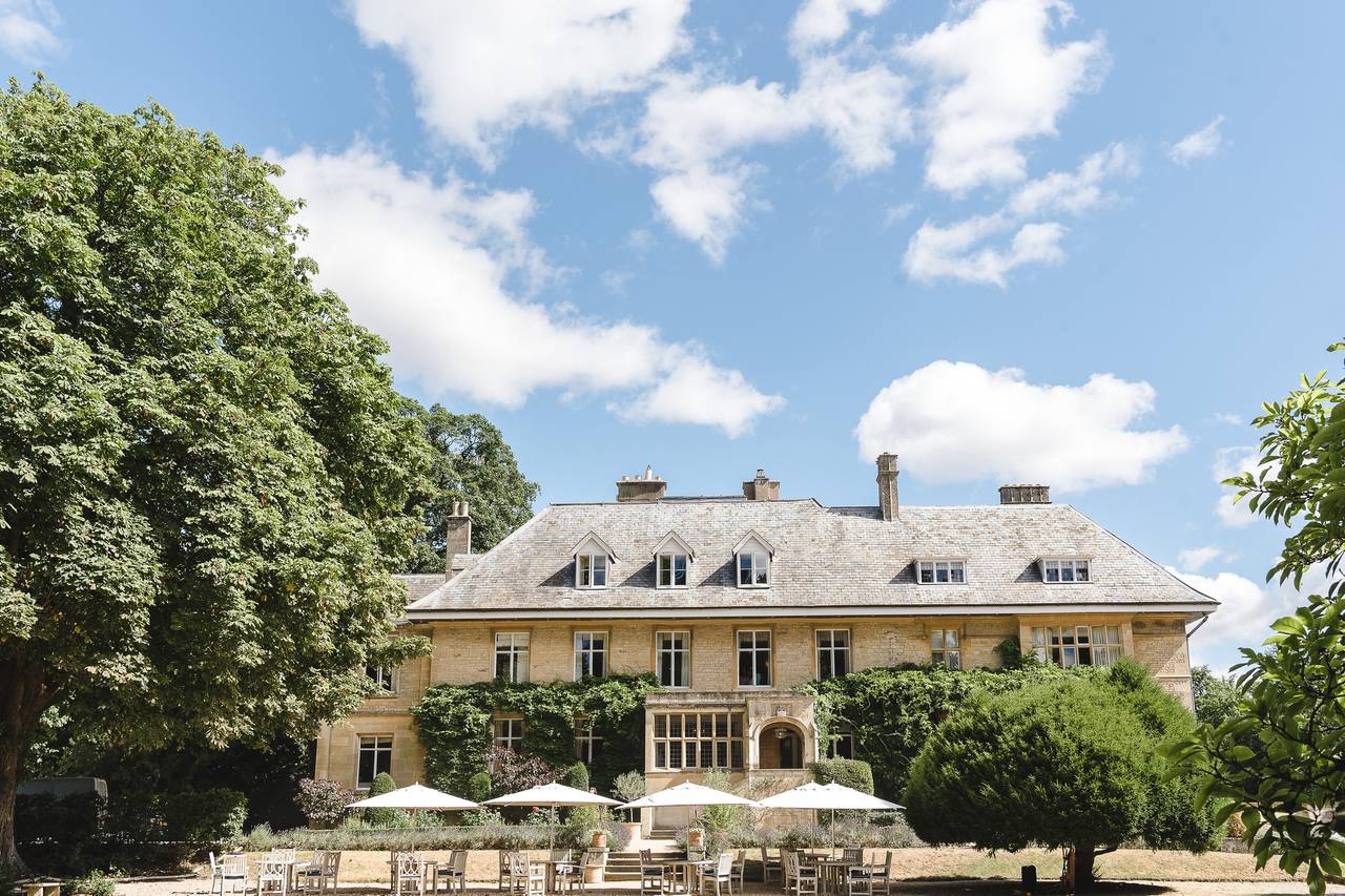 A picturesque house atop a hill overlooking the village of Linton, surrounded by lush greenery and clear blue skies.