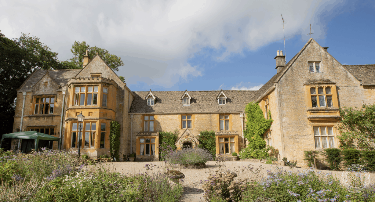 A picturesque house at the Cotswolds Hotel, surrounded by lush greenery and charming countryside scenery.