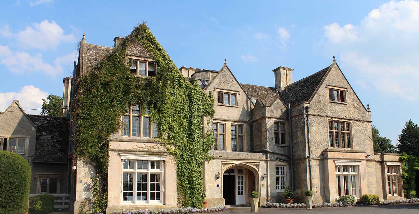 The exterior view of the Manor House Hotel in Oxfordshire, showcasing its elegant architecture and surrounding landscape.